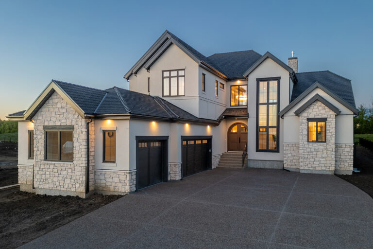 Large cream-colored residential home with EIFS cladding and stone masonry accents, showcasing modern exterior finishes in Edmonton.