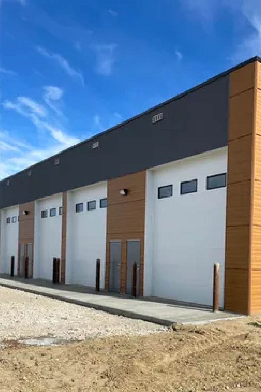 Commercial siding installation on large garage building with multiple overhead doors in Edmonton.