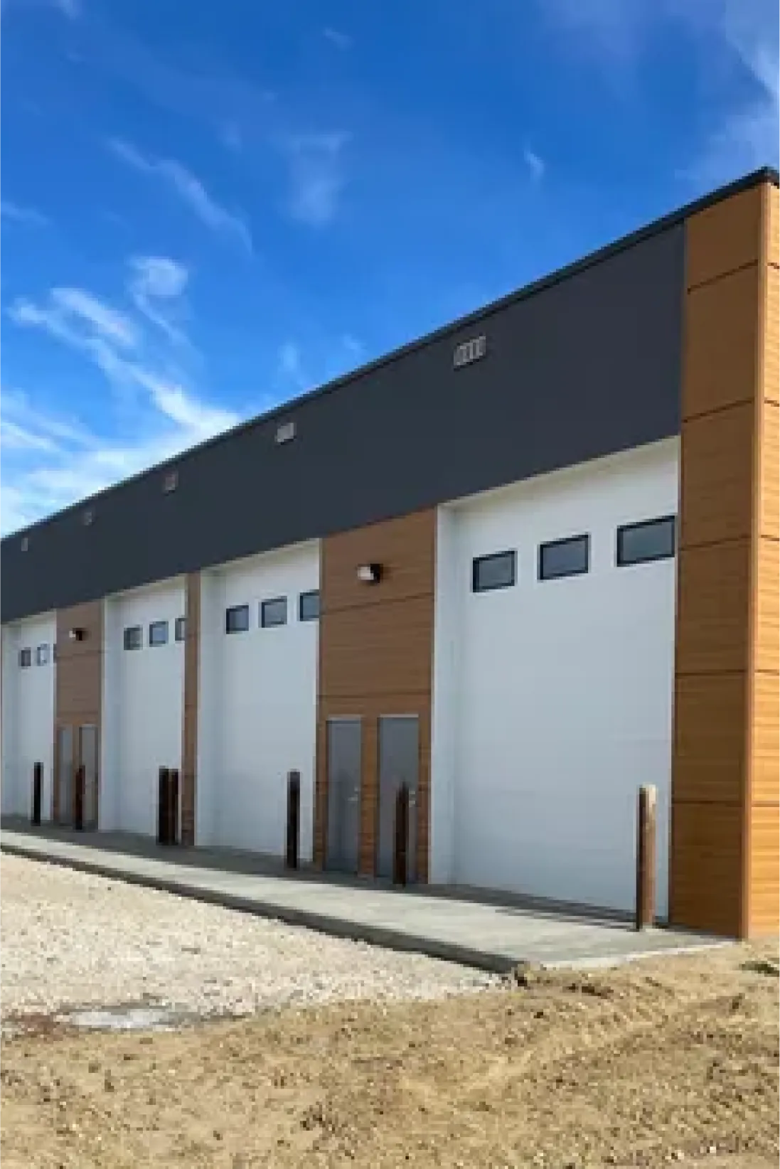 Commercial siding installation on large garage building with multiple overhead doors in Edmonton.