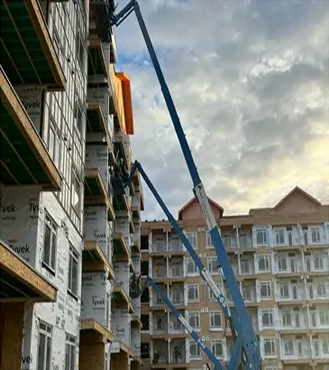 Siding installation on multi-family apartment building with cranes on site in Edmonton.