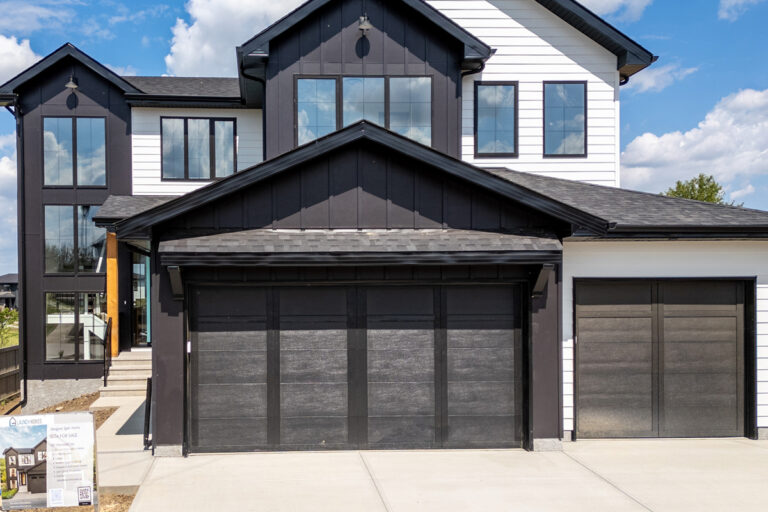 Modern two-story black-and-white house with large windows and a triple dark garage.